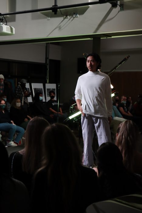 model posing in a fashion show wearing a white shirt and gray trousers