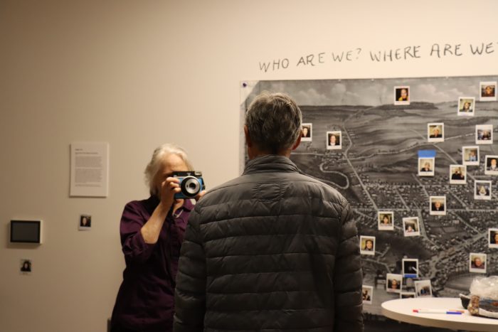 person with back to camera having their photo taken in front of a map